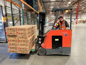 Warehouse worker (Romero) uses a forklift to unload cargo from a docked trailer at an EOS warehouse.