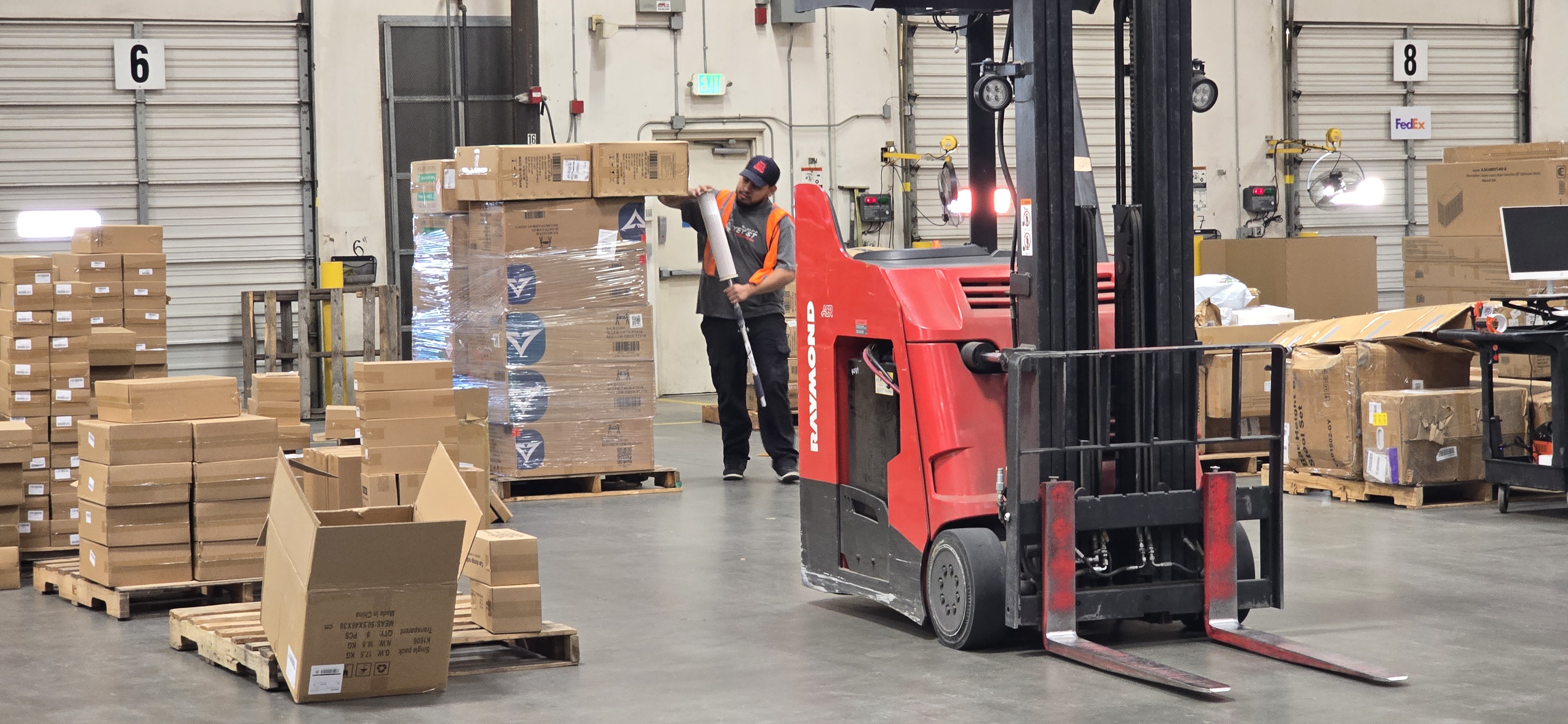 Worker shrink wrapping a pallet for outbound shipping inside EOS Southern California Warehouse.