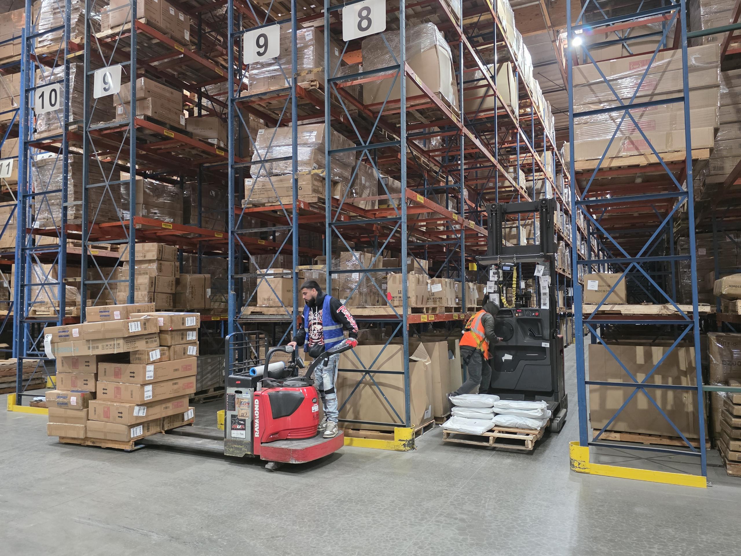 Pallet jack driver and reach operator working on fulfillment inside EOS Ontario warehouse.