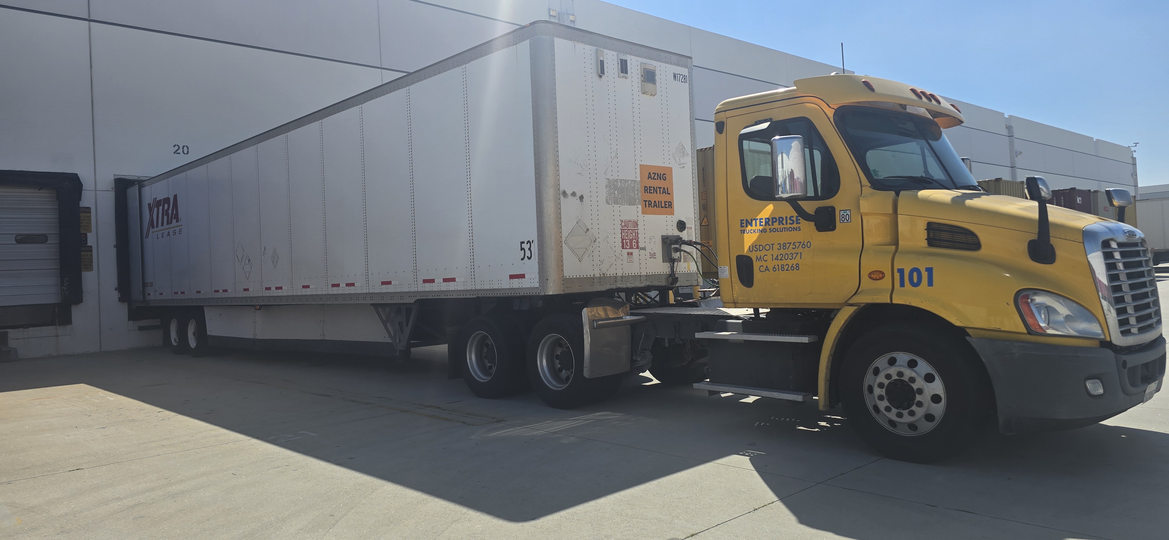 ETS tractor attached to a white trailer backed to an EOS warehouse dock.